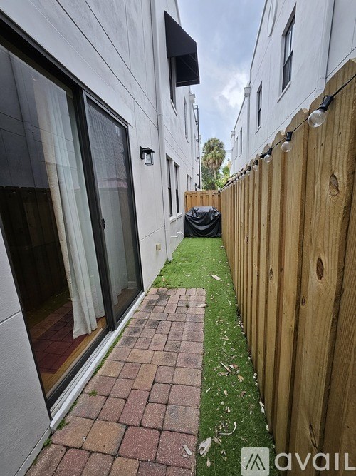 A narrow alley with a wooden fence on one side and a brick pathway.