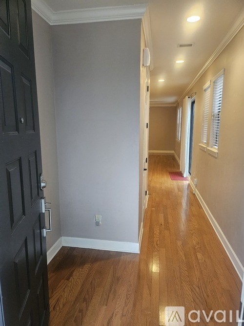 A hallway with wood floors and a black door.