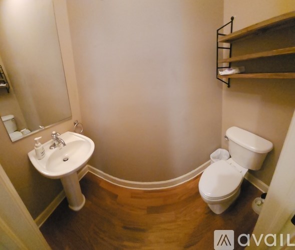 A small bathroom with a toilet, sink and shelves.