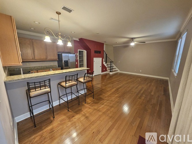 A kitchen with wooden floors and a bar area with two chairs.