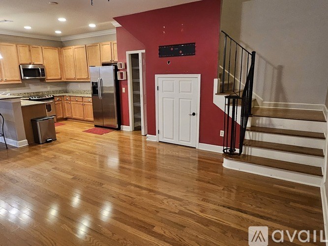 A kitchen with wooden floors and a red wall.