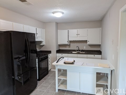 A kitchen with black appliances and white cabinets.