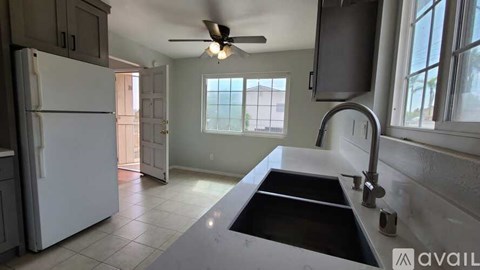 A kitchen with a white refrigerator and a black sink.