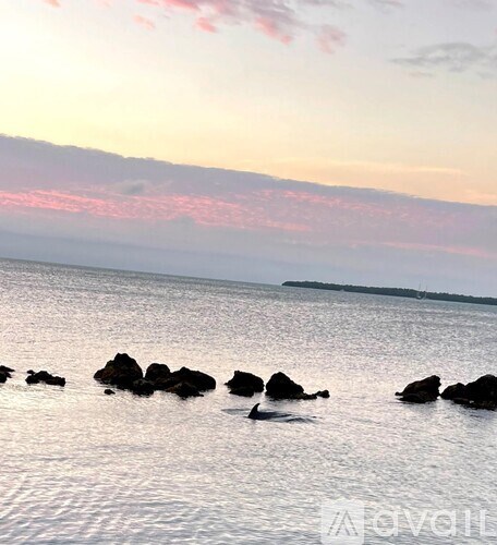A serene seascape with rocks in the foreground and a sunset sky.
