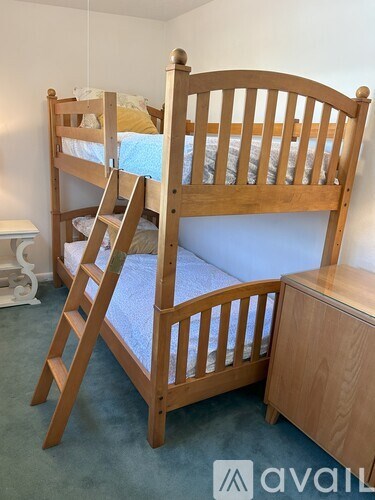 A wooden bunk bed with a ladder and a small table.