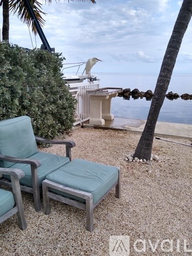 A chair and a table are on a patio overlooking the ocean.