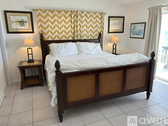 A bedroom with a large bed and two lamps.