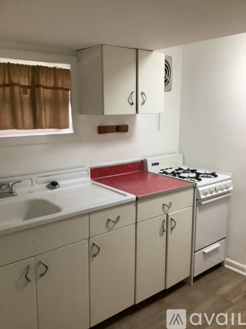 A kitchen with white cabinets and a red counter.