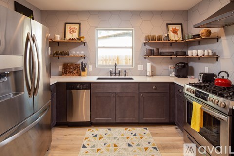 A kitchen with a stainless steel refrigerator and a black stove top oven.