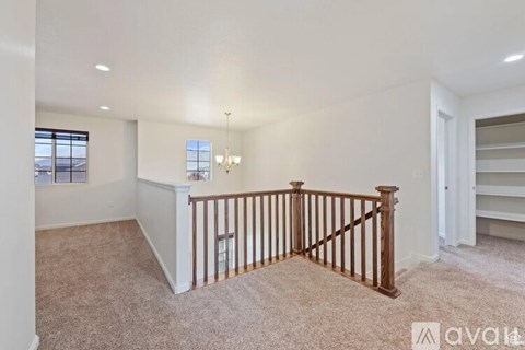 A spacious living room with a carpeted floor and a wooden railing.