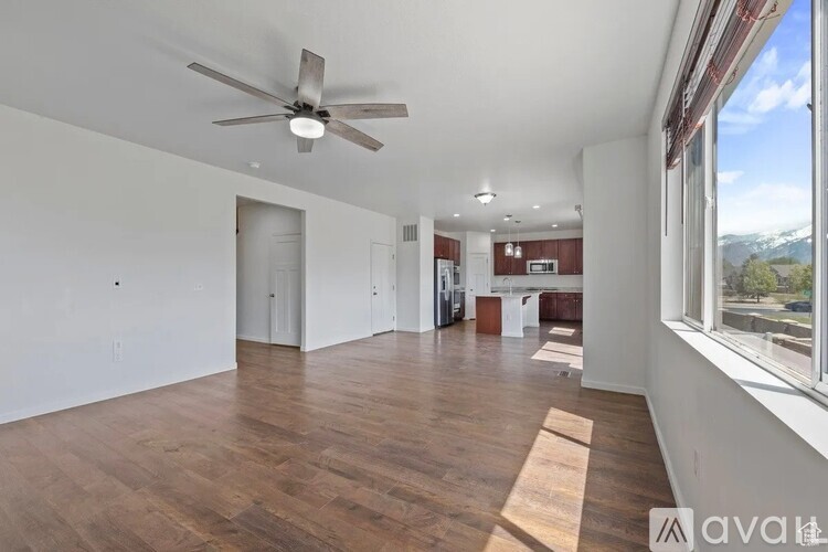 A spacious room with wooden floors and a ceiling fan.