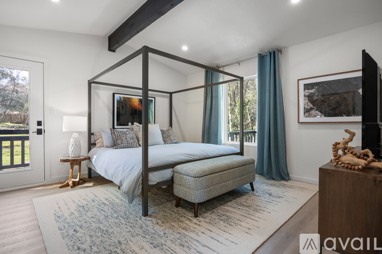 A bedroom with a four-poster bed and a window with blue curtains.