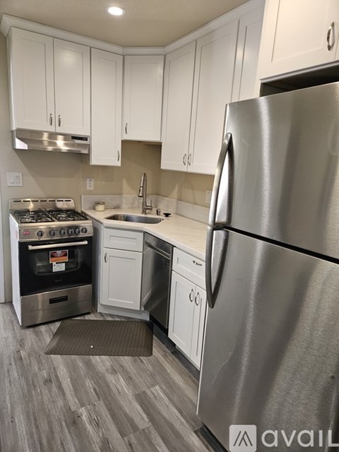 A modern kitchen with a stainless steel refrigerator and white cabinets.