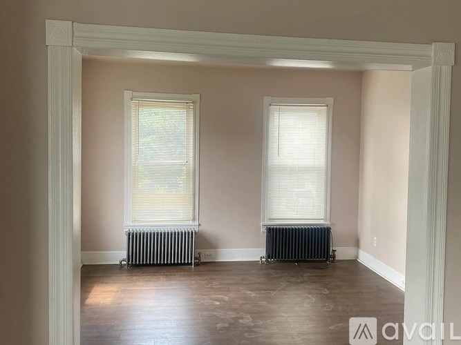 A room with two windows and radiators under the windows.