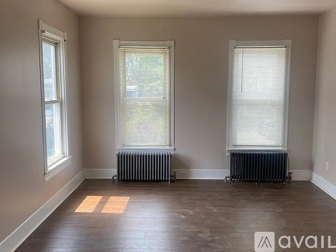 A room with two windows and two radiators on the floor.