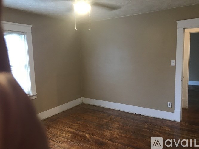 A room with wooden floors and a window on the left side.