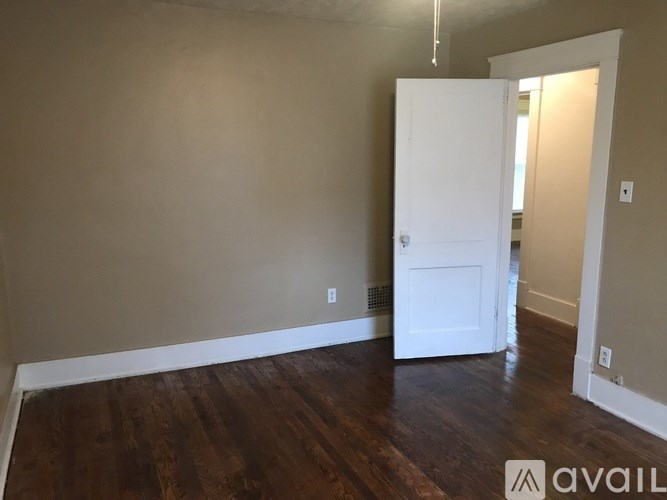 A room with a white door and wooden flooring.