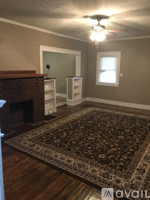 A room with a fireplace and a rug on the floor.