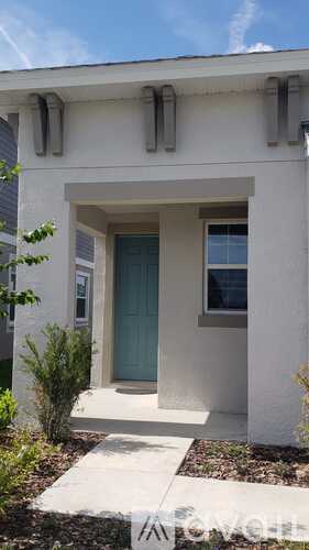 A white house with a blue door and a small window above it.