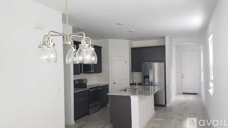 A modern kitchen with a center island and pendant lights.