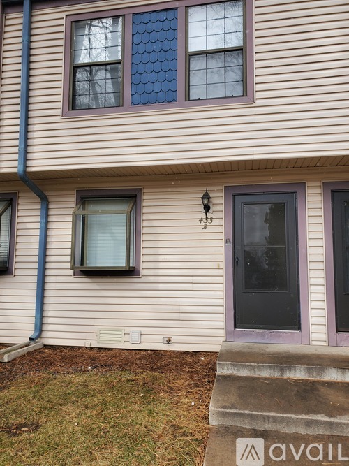 A house with a purple door and a black lamp on the wall.
