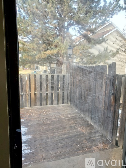 A wooden deck with a fence and a house in the background.
