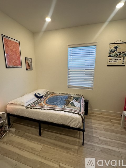 A bedroom with a bed and a picture of a wave on the wall.