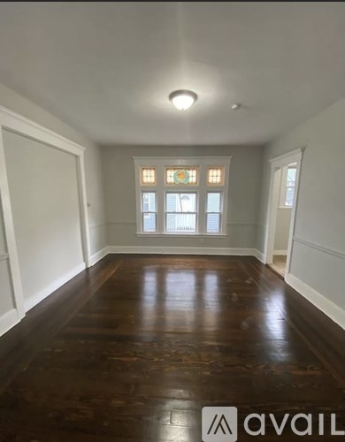 A room with wooden floors and a window with stained glass.