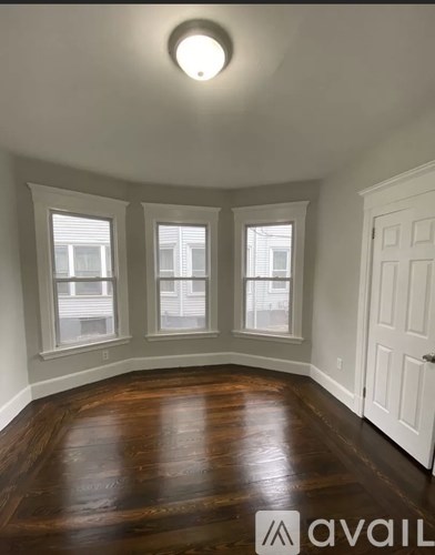A room with wooden floors and three windows.