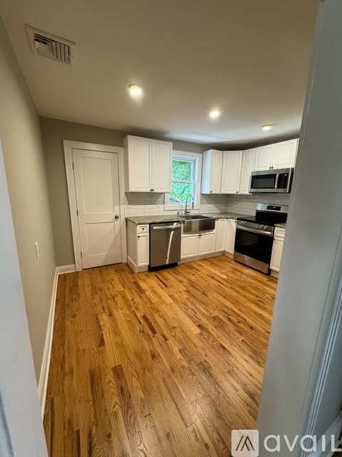 A kitchen with wooden floors and white cabinets.