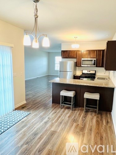 A kitchen with wooden floors and a counter with two stools.