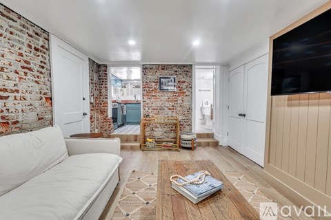 A living room with a white couch and a brick wall.