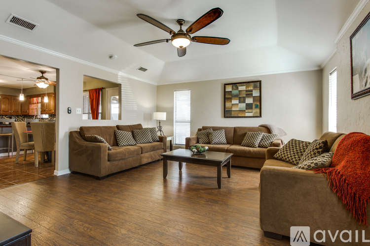 A living room with a brown couch and a ceiling fan.