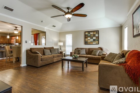 A living room with a brown couch and a ceiling fan.