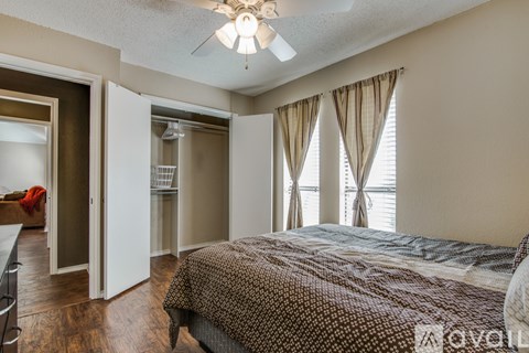 A bedroom with a bed, a ceiling fan, and a window with curtains.