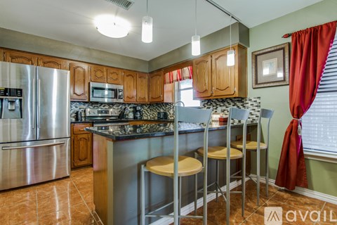 A kitchen with a refrigerator, microwave, and stove top oven.