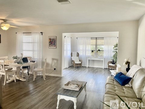 A living room with a white couch and a dining table with chairs.