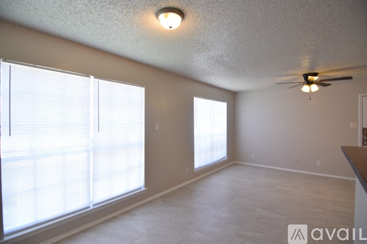 A room with a ceiling fan and a window with blinds.