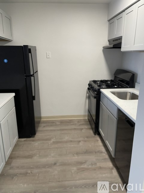 A black fridge and stove in a kitchen with white cabinets.
