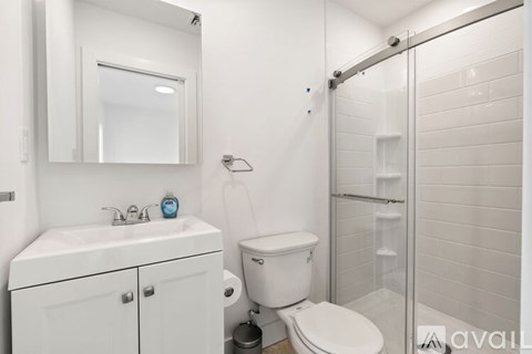 A bathroom with a toilet, sink, mirror, and shower.