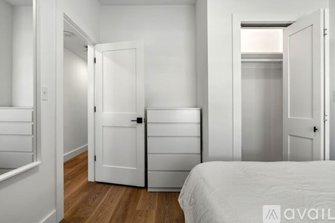 A white bedroom with a bed, dresser, and wardrobe.