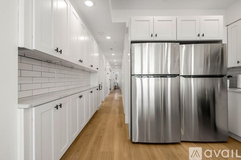 A modern kitchen with white cabinets and a large stainless steel refrigerator.
