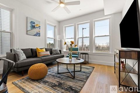 A living room with a grey sofa, a coffee table, and a ceiling fan.