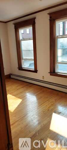 A room with wooden floors and two windows.