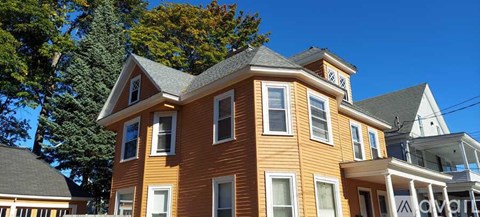 A large two-story house with a brown exterior and white trim.