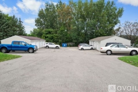 A parking lot with a blue car and a white car parked in front of a building.