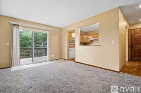 A spacious living room with a sliding glass door leading to a balcony.