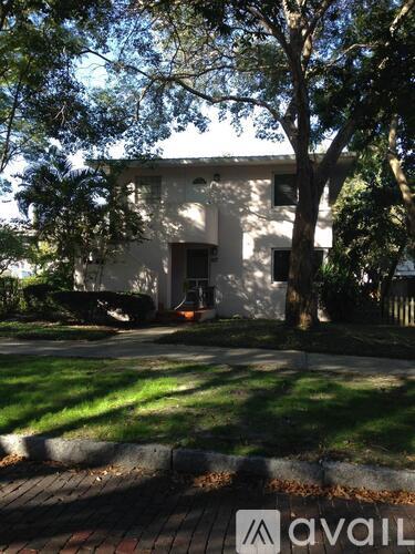 A white house with a tree in front of it.