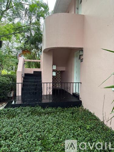 A pink building with a balcony and a black railing.