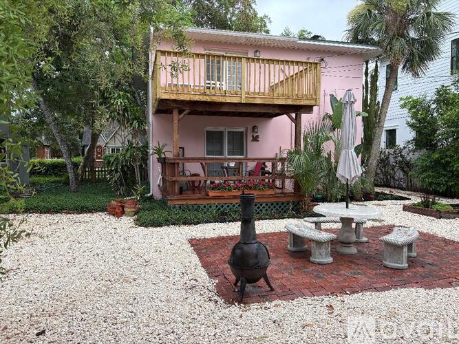 A pink house with a balcony and a patio with a table and chairs.